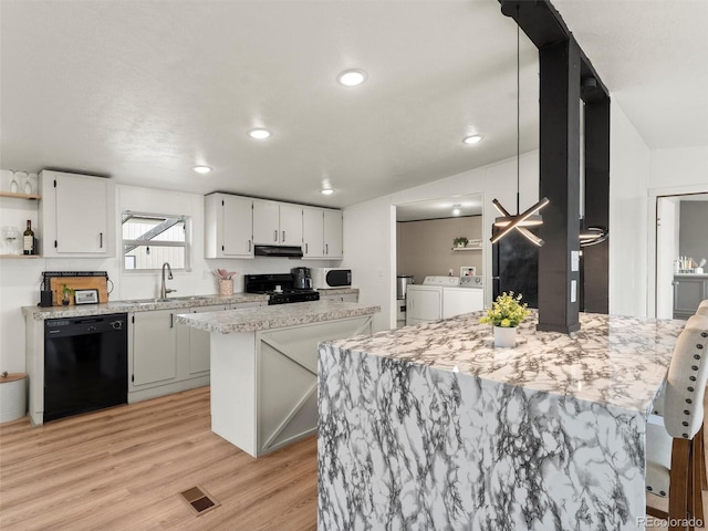 69501 E 72nd Ave, Byers, CO 80103 - kitchen with black appliances, separate washer and dryer, open shelves, light wood-type flooring, and a peninsula