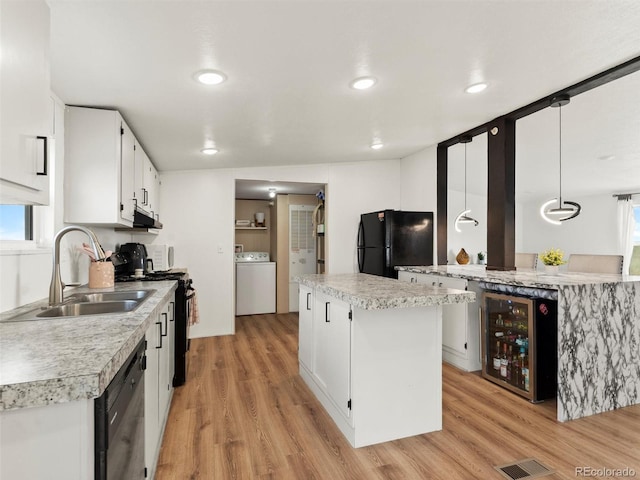 69501 E 72nd Ave, Byers, CO 80103 - kitchen featuring black appliances, washer / dryer, wine cooler, light wood-style floors, and recessed lighting