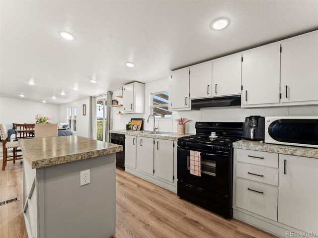 69501 E 72nd Ave, Byers, CO 80103 - kitchen featuring black appliances, under cabinet range hood, a center island, light wood finished floors, and white cabinetry