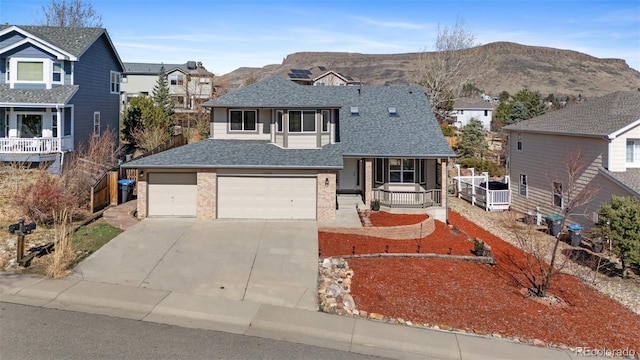 traditional-style home featuring a mountain view, covered porch, a shingled roof, brick siding, and concrete driveway