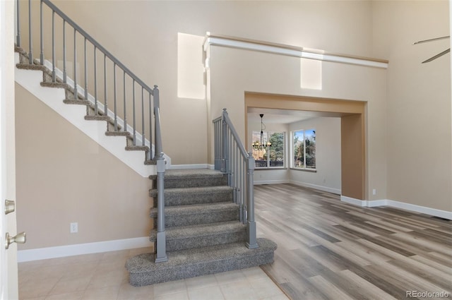 foyer featuring stairs, a notable chandelier, and baseboards