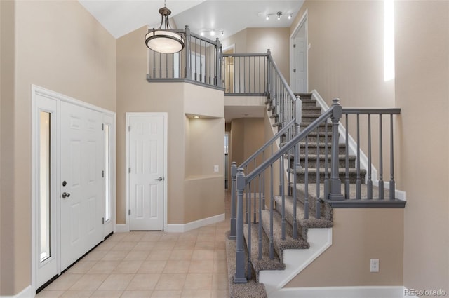 tiled foyer entrance featuring a high ceiling and baseboards