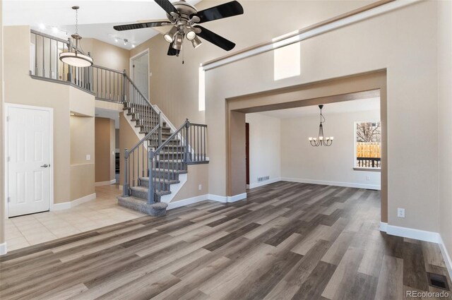 unfurnished living room with stairs, visible vents, baseboards, and wood finished floors