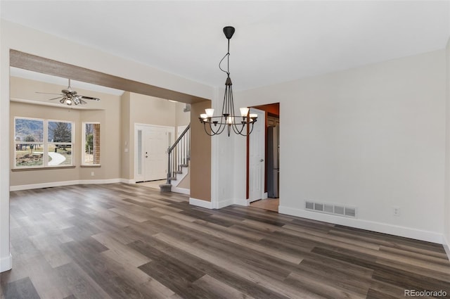 unfurnished dining area with dark wood finished floors, visible vents, stairway, baseboards, and ceiling fan with notable chandelier