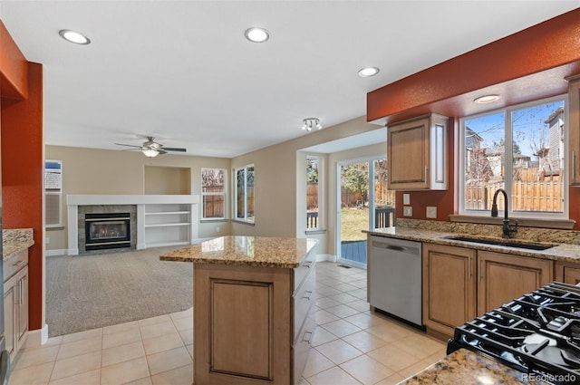 kitchen featuring recessed lighting, a fireplace with flush hearth, a kitchen island, a sink, and stainless steel dishwasher