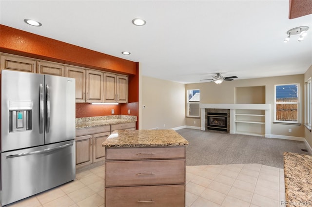 kitchen with a fireplace, stainless steel refrigerator with ice dispenser, light tile patterned floors, a ceiling fan, and light carpet