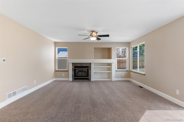 unfurnished living room featuring light carpet, visible vents, baseboards, ceiling fan, and a fireplace