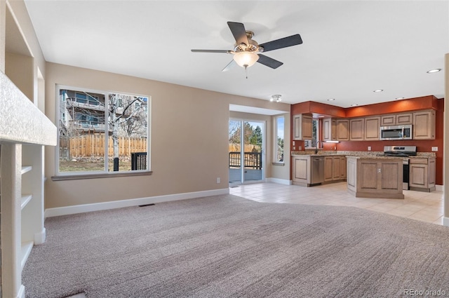 kitchen featuring light carpet, baseboards, a kitchen island, and appliances with stainless steel finishes