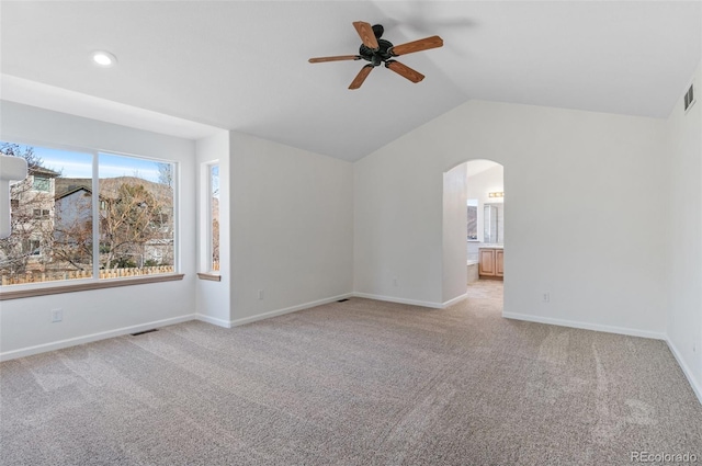 interior space featuring arched walkways, light carpet, vaulted ceiling, and baseboards