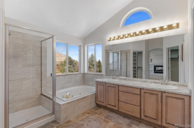 bathroom with a jetted tub, a shower stall, double vanity, and a sink