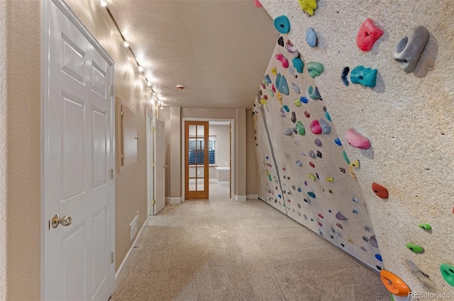 interior space with a textured ceiling, carpet flooring, visible vents, baseboards, and french doors