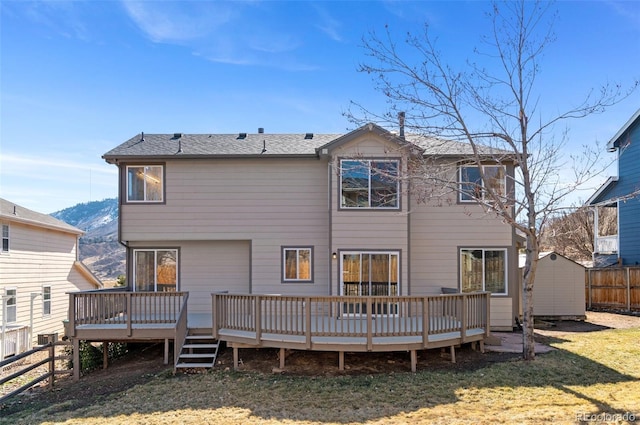 back of property with a yard, an outbuilding, fence, and a wooden deck