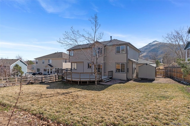 rear view of house featuring a deck with mountain view, a yard, an outdoor structure, and a fenced backyard