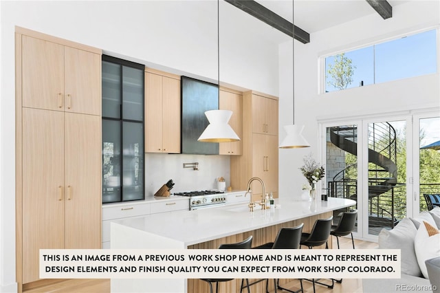 kitchen with a kitchen breakfast bar, light brown cabinetry, beamed ceiling, and sink