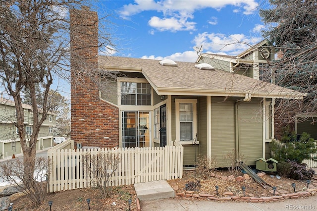 view of front of home with roof with shingles and a fenced front yard