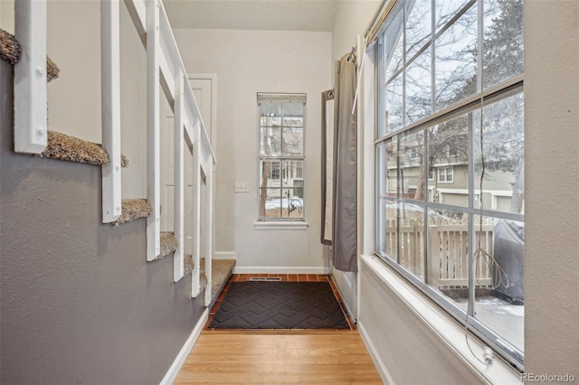 entryway featuring light wood-style flooring, baseboards, and a textured ceiling