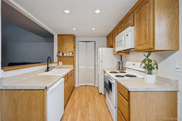 kitchen with recessed lighting, white appliances, a sink, light countertops, and light wood finished floors