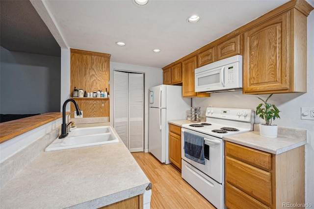 kitchen featuring light wood-style flooring, recessed lighting, white appliances, a sink, and light countertops