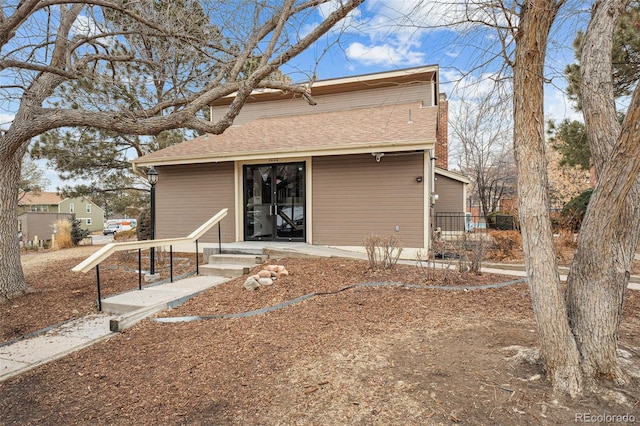 back of property featuring roof with shingles