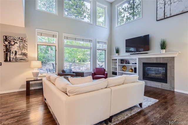 living room with dark wood-type flooring, a high ceiling, and a healthy amount of sunlight