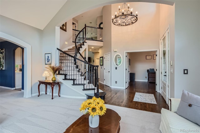 entryway with dark wood-type flooring, a chandelier, and high vaulted ceiling