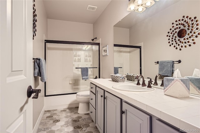 full bathroom with vanity, toilet, and enclosed tub / shower combo