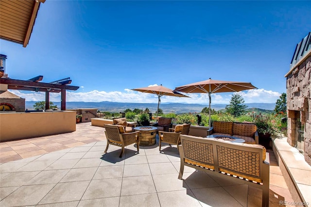 view of patio / terrace featuring a mountain view and an outdoor living space with a fire pit