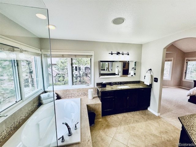 bathroom featuring tiled tub, tile patterned floors, vanity, and a textured ceiling