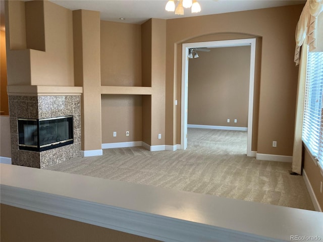 unfurnished living room with ceiling fan, a tile fireplace, and carpet floors