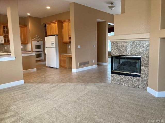 kitchen with light carpet, white appliances, and a fireplace