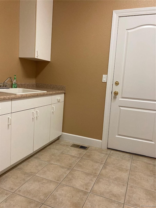 laundry area featuring light tile patterned flooring and sink