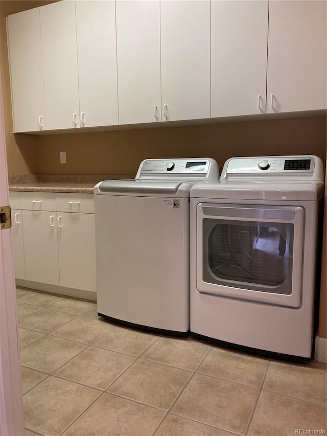 washroom featuring separate washer and dryer, cabinets, and light tile patterned flooring