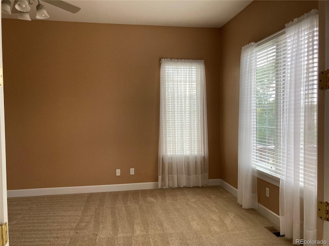 empty room with light carpet, a healthy amount of sunlight, and ceiling fan