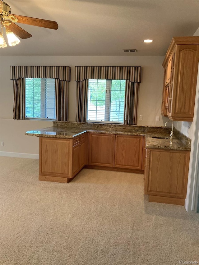 kitchen featuring kitchen peninsula, sink, light carpet, and ceiling fan