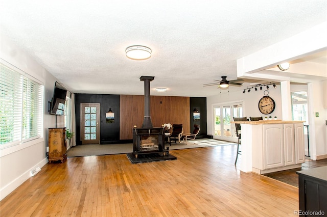 7684 Beverly Blvd, Castle Pines, CO 80108 - living room with a wood stove, light wood-type flooring, a textured ceiling, baseboards, and ceiling fan