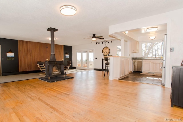 7684 Beverly Blvd, Castle Pines, CO 80108 - unfurnished living room with light wood finished floors, a wood stove, and a ceiling fan