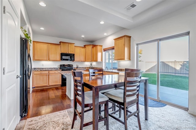 kitchen featuring dark wood-style flooring, visible vents, recessed lighting, light stone countertops, and black appliances