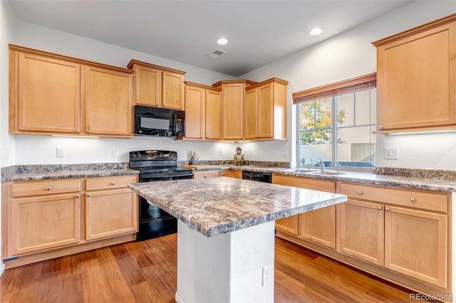 kitchen with light wood-style flooring, light brown cabinetry, a sink, and black appliances