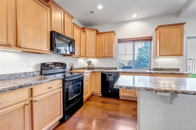 kitchen with wood finished floors, light brown cabinets, visible vents, and black appliances