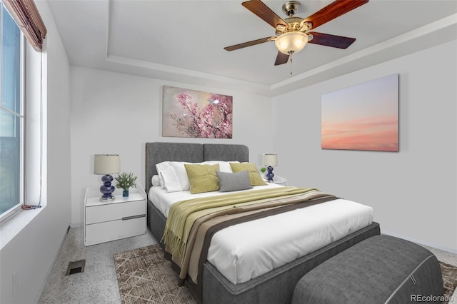 bedroom featuring speckled floor, baseboards, a tray ceiling, and visible vents