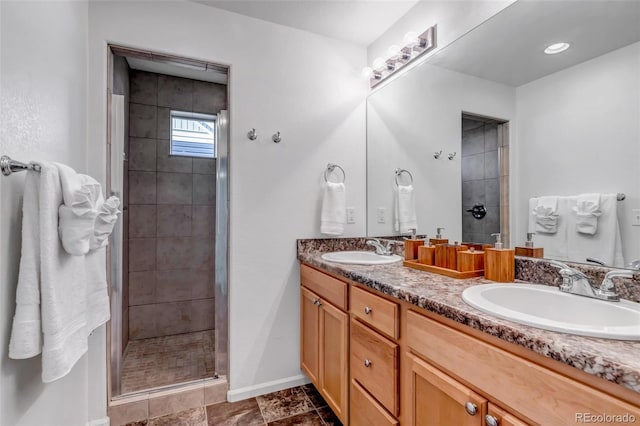 bathroom featuring double vanity, a shower stall, baseboards, and a sink