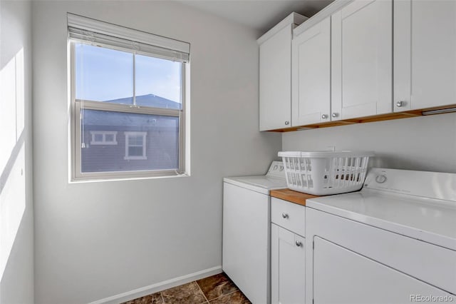 washroom with stone finish flooring, baseboards, cabinet space, and independent washer and dryer