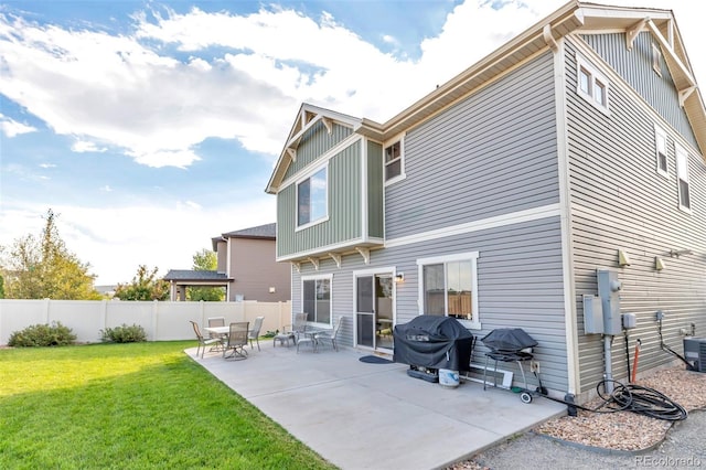 rear view of house featuring board and batten siding, a yard, a patio area, and fence
