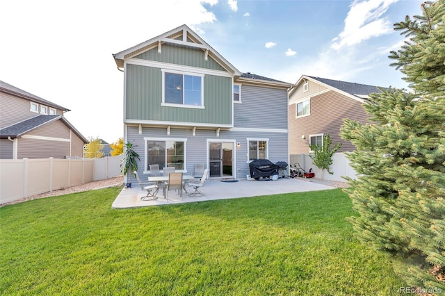 rear view of property with a lawn, a patio area, board and batten siding, and a fenced backyard
