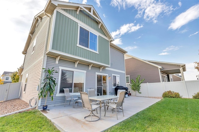 back of house featuring board and batten siding, a yard, a patio area, and a fenced backyard