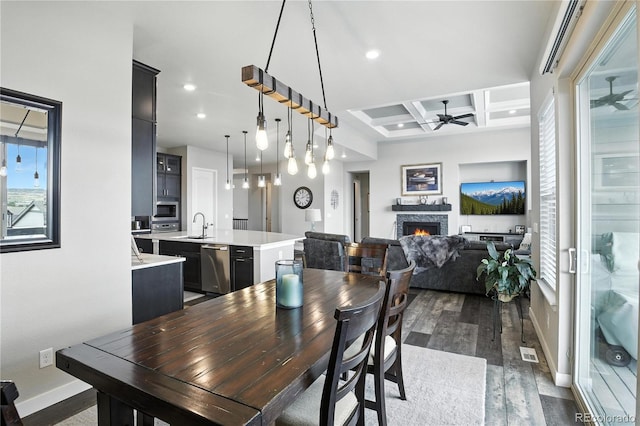 9538 Bear River St, Littleton, CO 80125 - dining space with a ceiling fan, dark wood finished floors, coffered ceiling, a warm lit fireplace, and recessed lighting