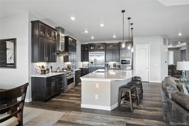 9538 Bear River St, Littleton, CO 80125 - kitchen featuring wall chimney range hood, built in appliances, tasteful backsplash, light countertops, and recessed lighting