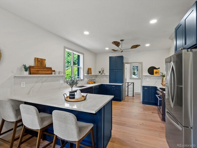 883 S Downing St, Denver, CO 80209 - kitchen featuring stainless steel appliances, open shelves, blue cabinetry, a peninsula, and light wood-style floors