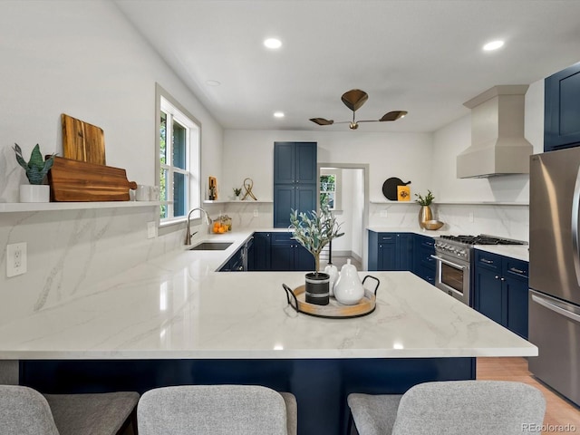 883 S Downing St, Denver, CO 80209 - kitchen with open shelves, blue cabinets, wall chimney range hood, appliances with stainless steel finishes, and a peninsula