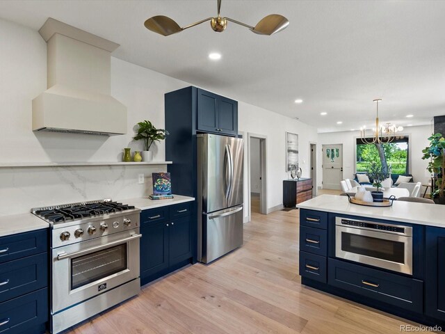 883 S Downing St, Denver, CO 80209 - kitchen featuring appliances with stainless steel finishes, blue cabinets, custom range hood, a chandelier, and recessed lighting